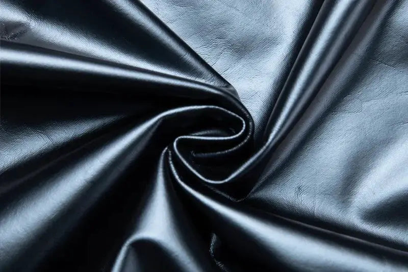 Black shiny faux leather fabric close-up with soft, dramatic folds