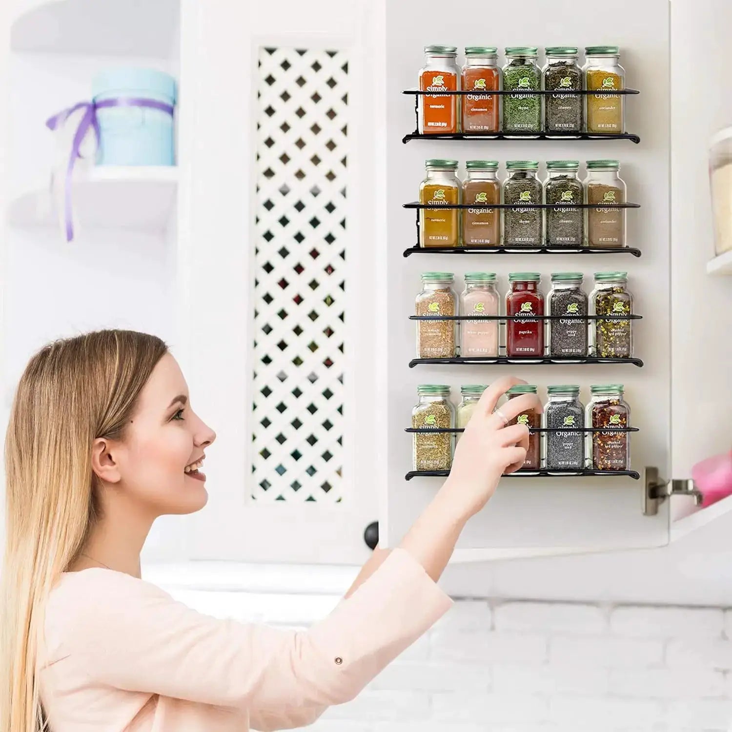 Iron four-tier wall-mounted spice rack with black metal shelves and glass jars with green lids.
