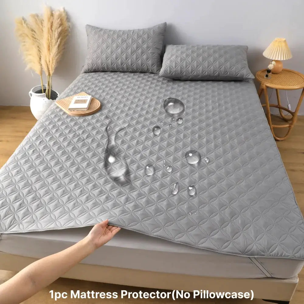 Waterproof mattress protector with elastic band on grey quilted bed pad; soft and breathable.