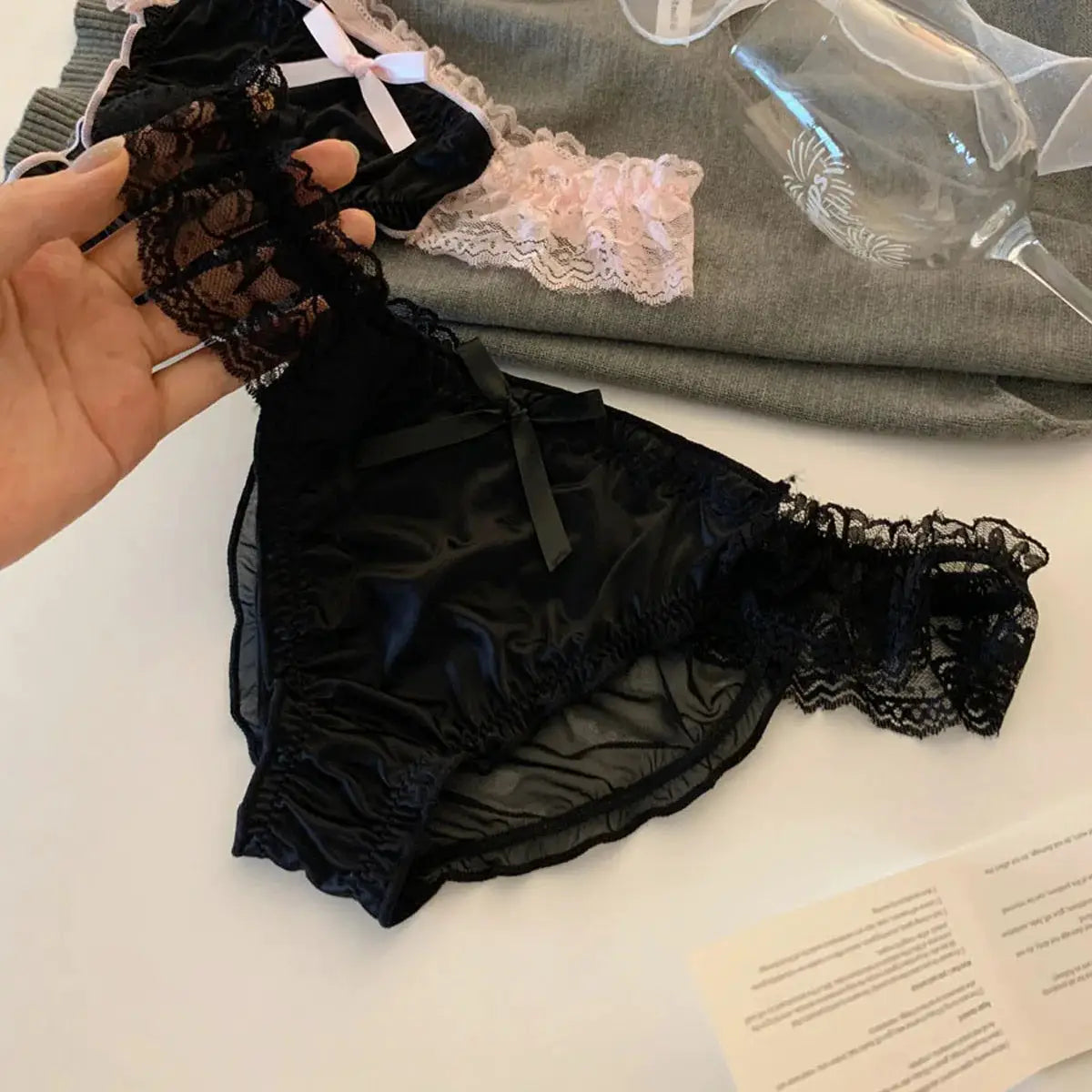 Women's black satin panty with lace trim, bow detail, and sheer lace sides