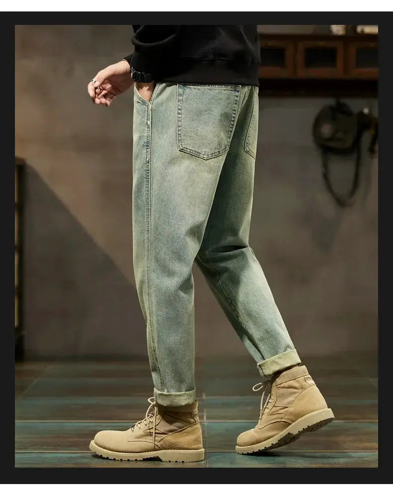 Men's loose blue denim harem pants with rolled cuffs and tan hiking boots in a casual Harajuku style