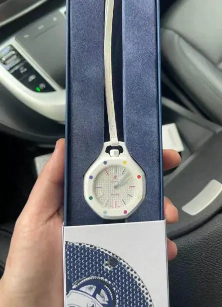 Watch in blue gift box with white dial, multicolor markers, and cream strap.