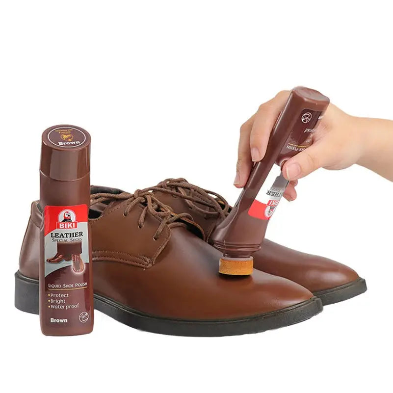 Leather shoe polish bottle by BIKI; brown liquid with sponge applicator beside brown dress shoes