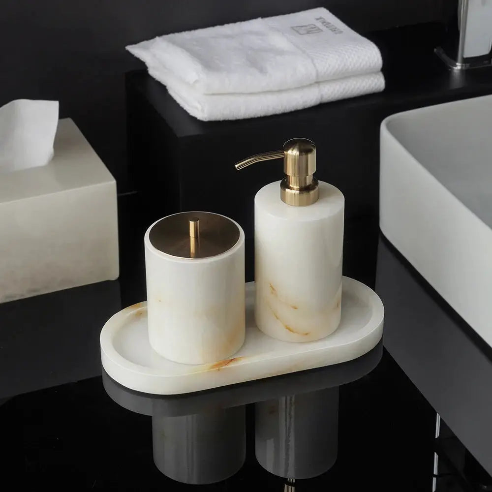 Two-piece white onyx marble bathroom set with gold-tone soap dispenser and tissue box holder on oval marble tray