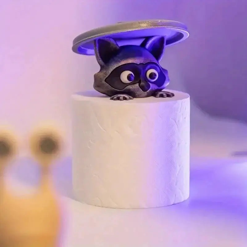 Toilet paper holder featuring a gray raccoon figure perched on a white roll