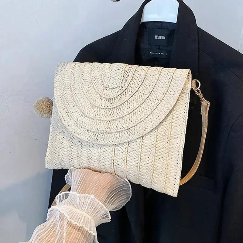 Handmade straw crossbody bag with envelope flap, beige woven texture and pom-pom accent