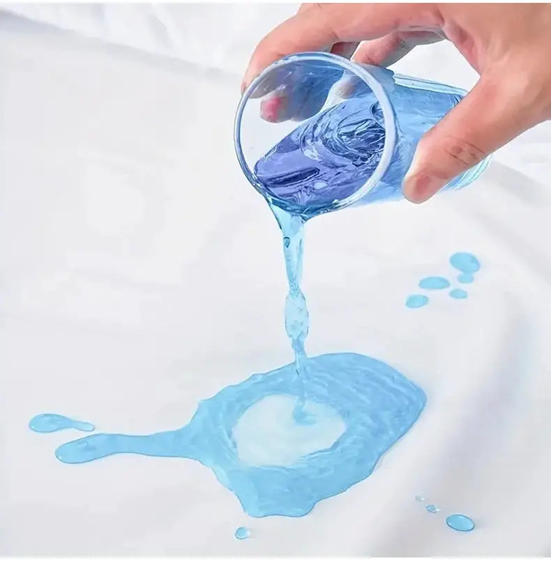 Waterproof mattress protector shown in action with blue liquid pouring onto a white fitted sheet