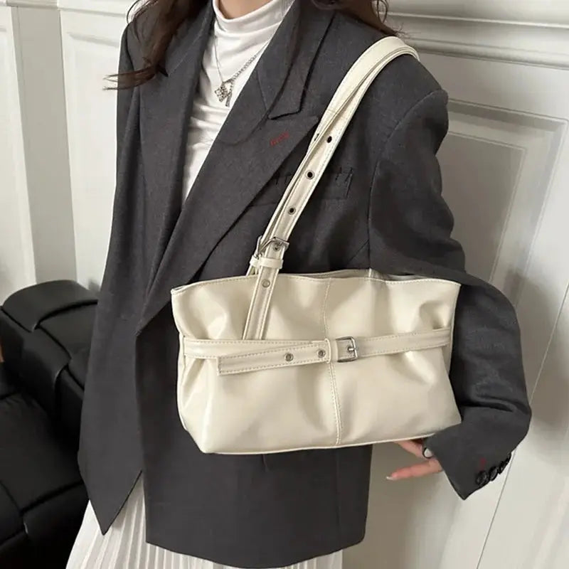 Beige leather handbag with belt-buckle strap and adjustable shoulder strap by Simples Market