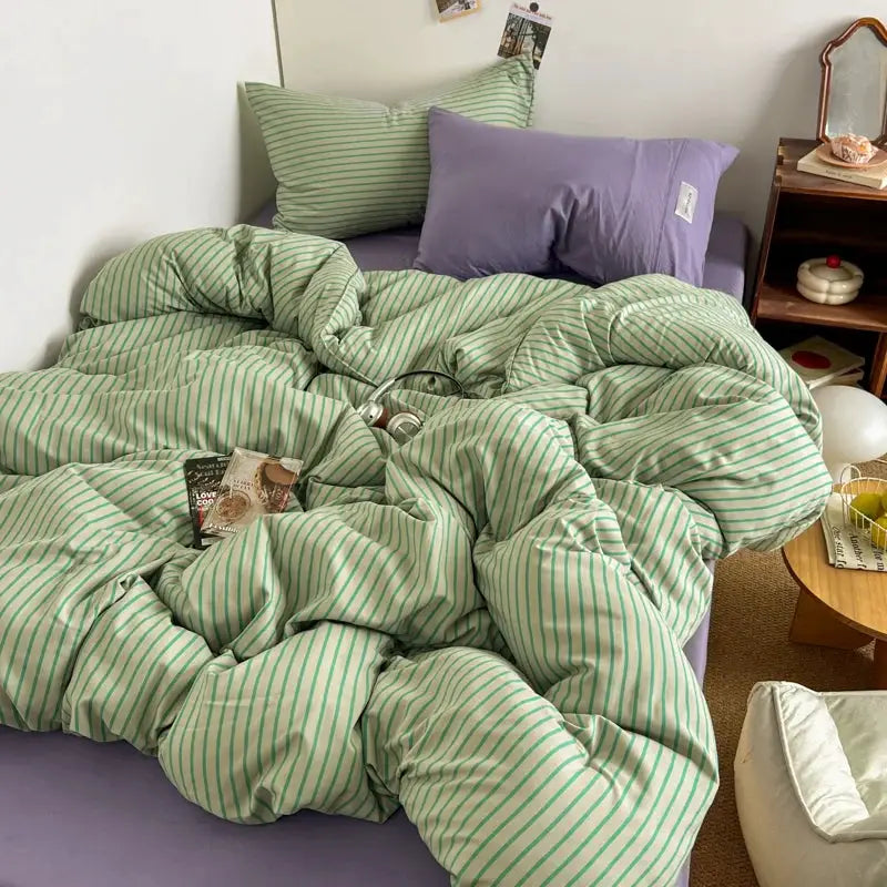 Bedding set with green striped duvet cover, lavender bedsheet and matching pillowcases on a bed