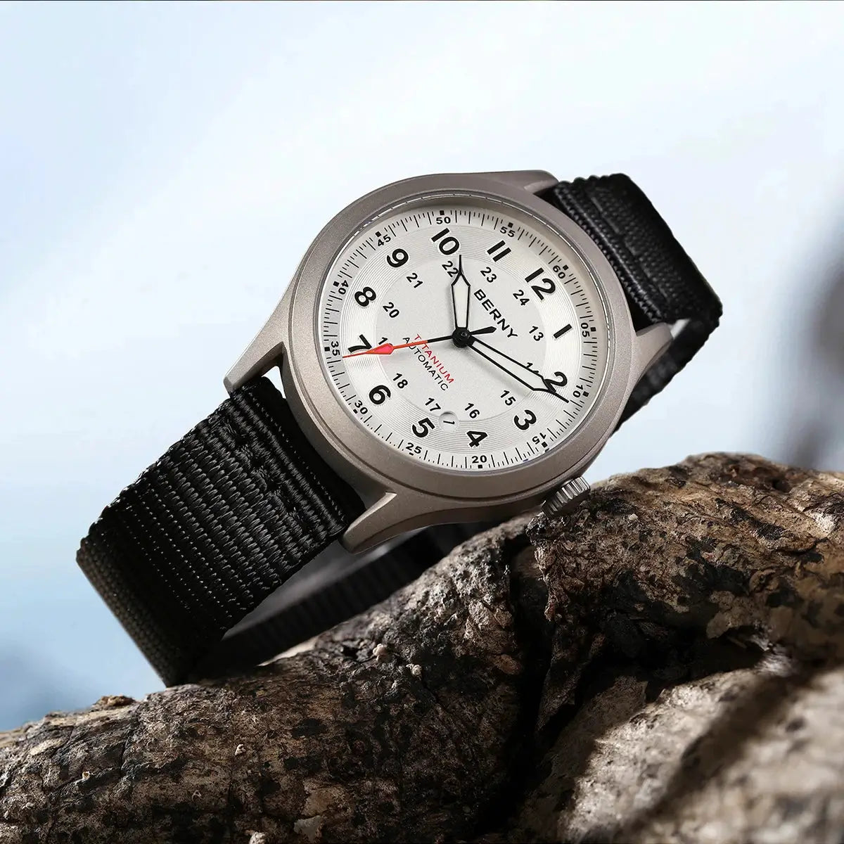 BERNY automatic titanium men's watch with black nylon strap, silver dial, luminous hands, 10ATM, on a rock.
