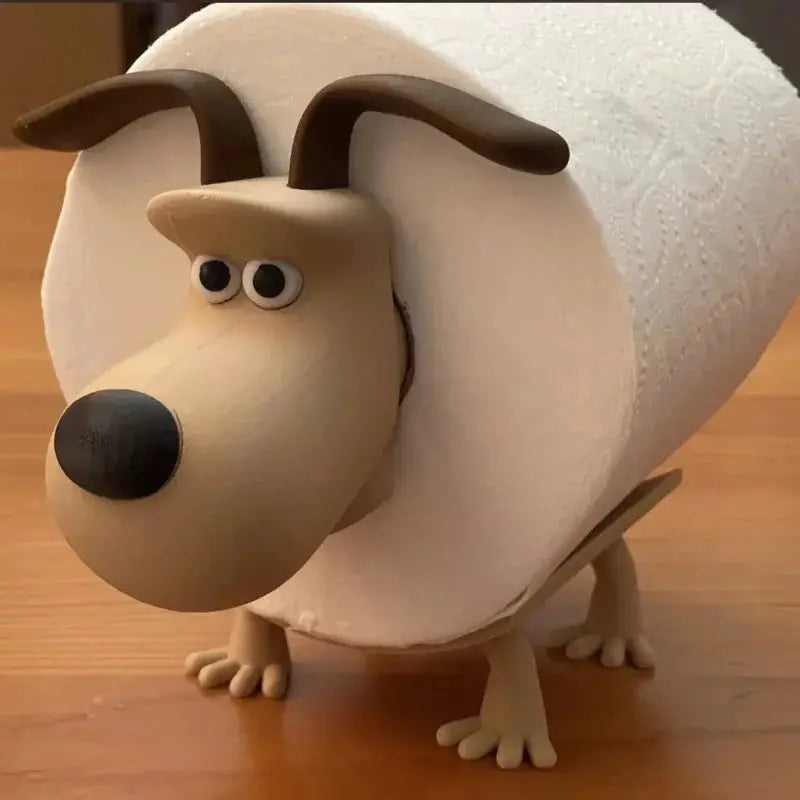 Dog-shaped toilet paper holder; beige figure with brown ears and a black nose, toilet paper wrapped around its body.