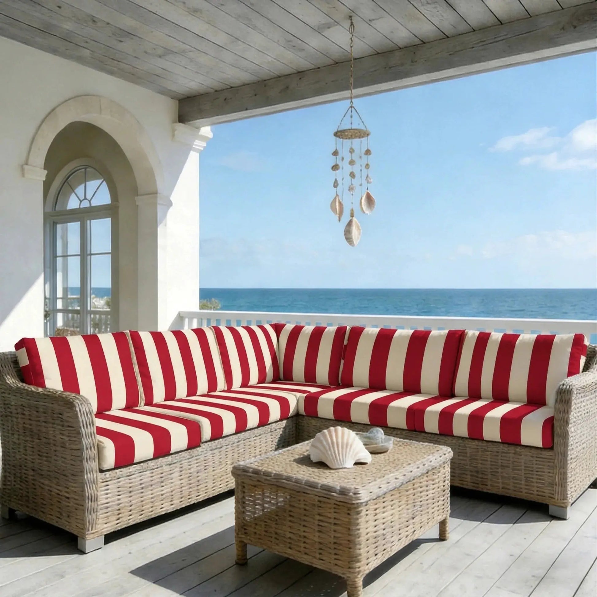 Outdoor wicker sofa cushions with red and white stripes on a seaside patio.