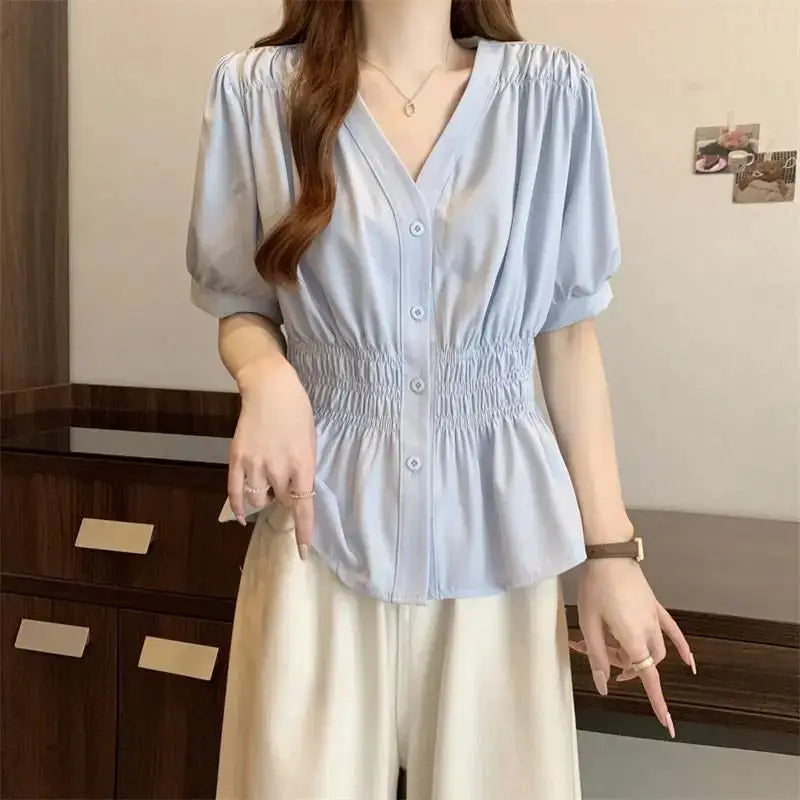 Light blue women's blouse with puff sleeves, elastic smocked waist, V-neck and button-front.