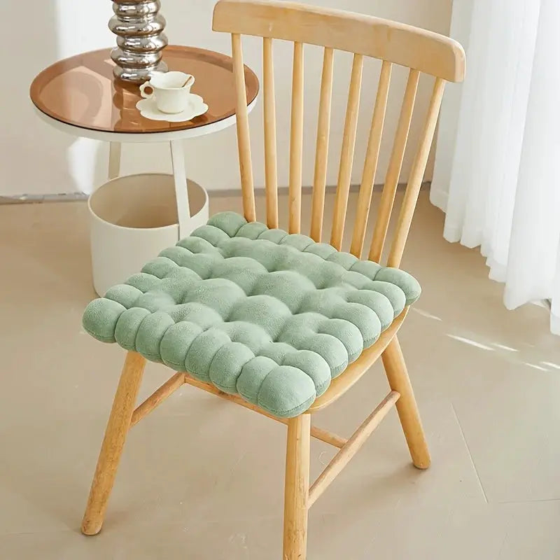 Large biscuit-shaped plush chair cushion in mint green with bubble tufting on a wooden chair.