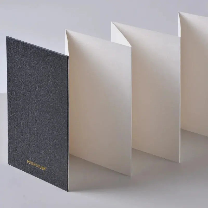 Mini watercolor sketchbook with dark textured cover and foldable white pages, travel painting notebook