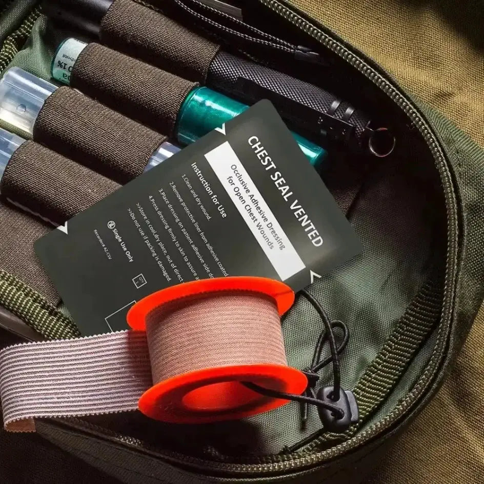 Chest Seal Vented emergency wound kit card with orange tape spool and beige strap in a green tactical bag