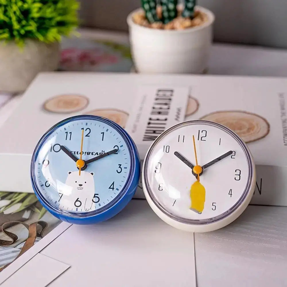 Two mini round quartz clocks, 7 cm each: blue bear design and white with yellow tag