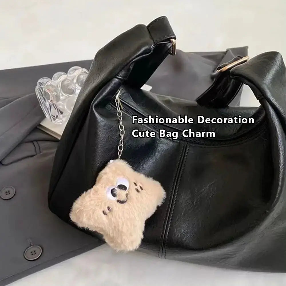 Trendy black PU leather slouchy shoulder bag with beige fluffy bag charm, large-capacity retro hobo tote.