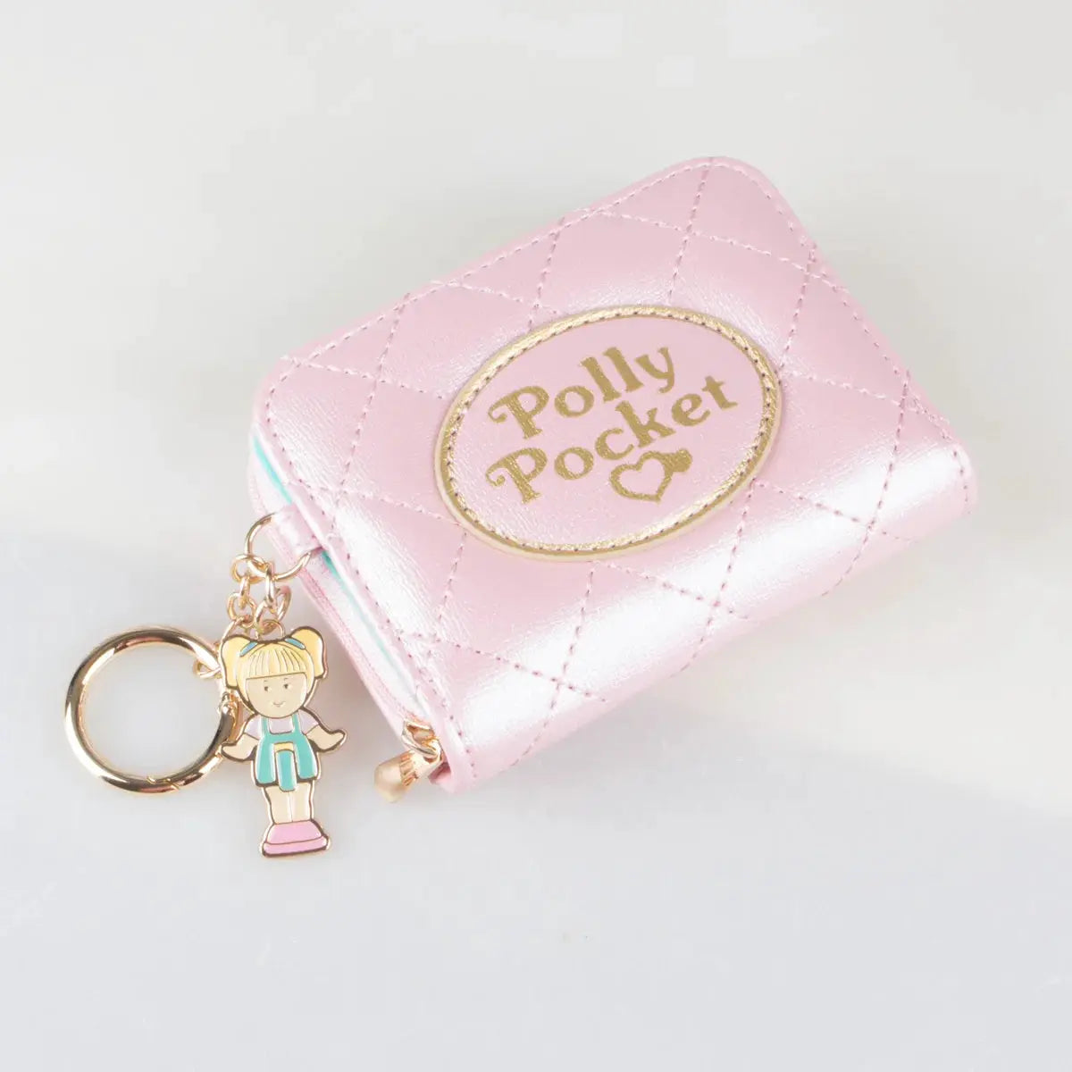 Pink quilted zipper wallet with a gold Polly Pocket patch and a single attached charm on a keychain