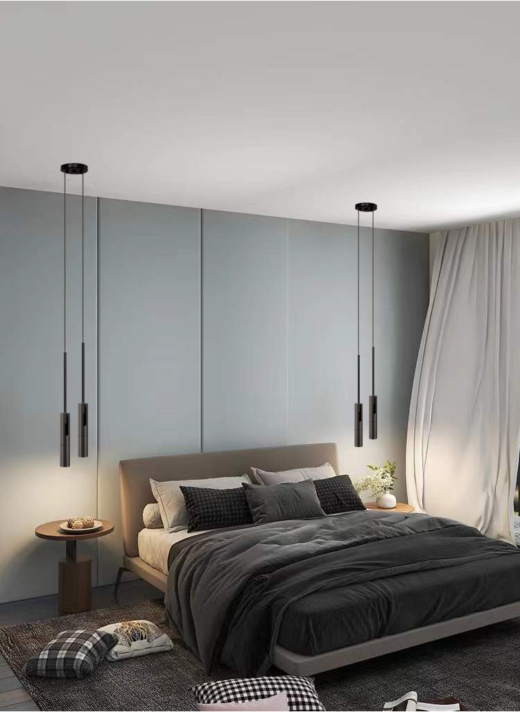 Minimalist LED hanging pendant lights by Simples Market, black cylindrical pair over a bedroom bed