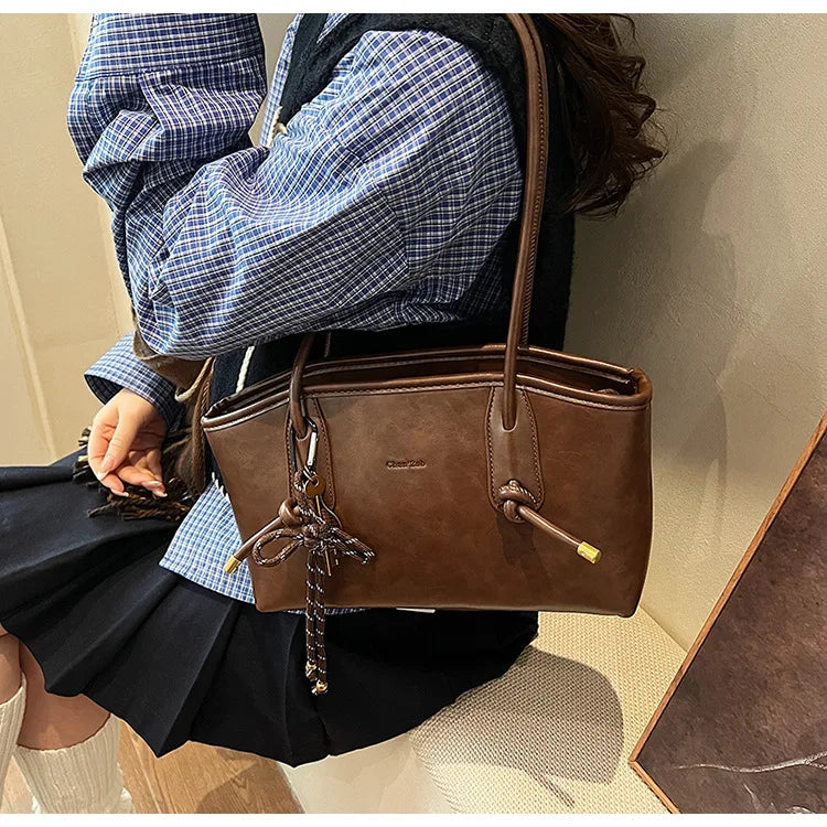 Simples Market PU leather shoulder bag in brown with tassel charm and long shoulder strap.