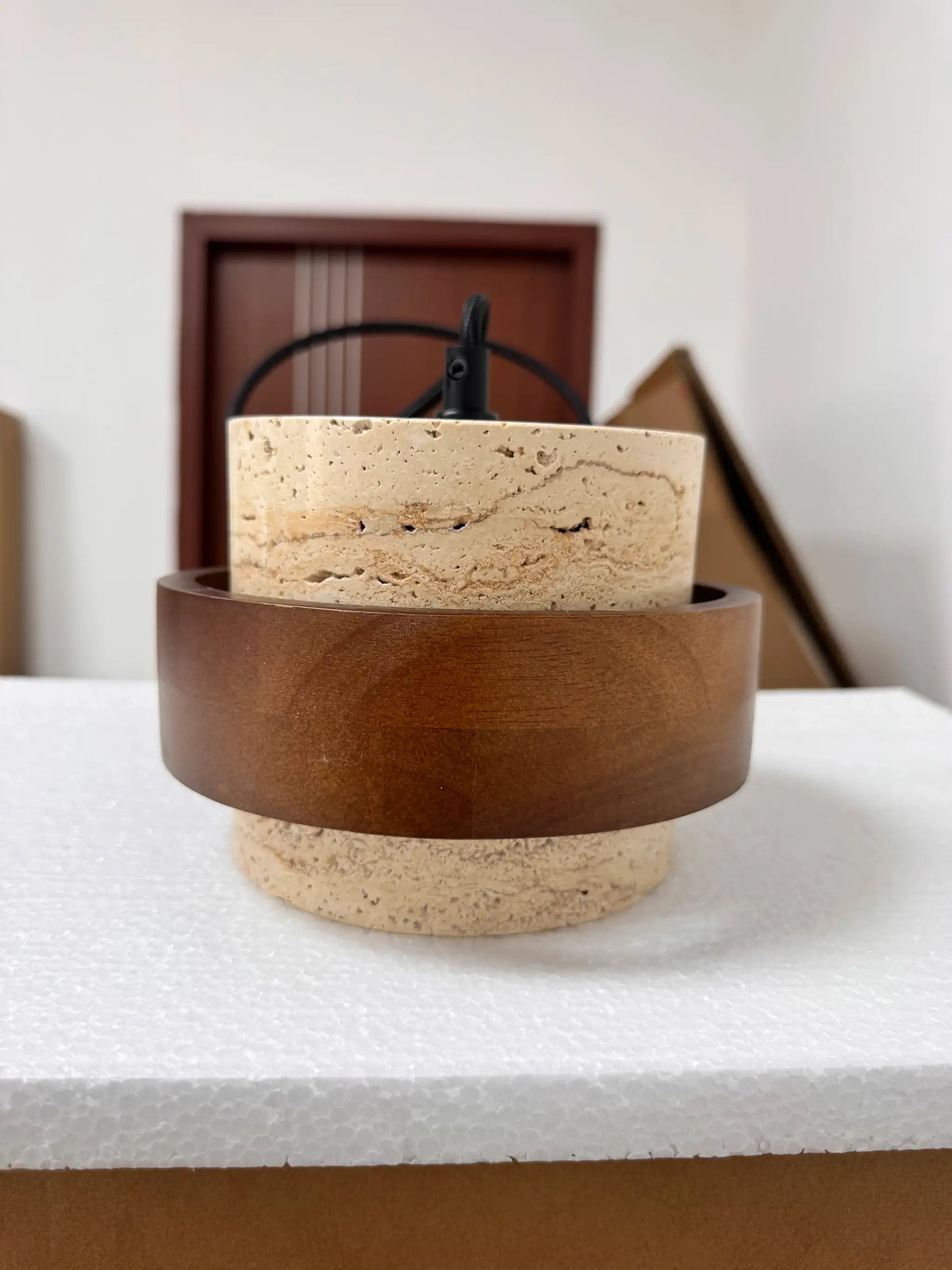 Pendant lamp with beige travertine stone base and dark brown metal ring, Japanese wabi-sabi style.