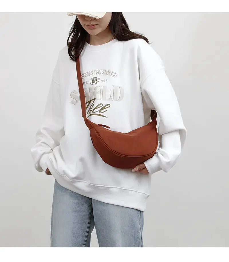 Nylon crossbody bag, crescent dumpling shape in warm brown, large-capacity zipper bag worn under the arm.