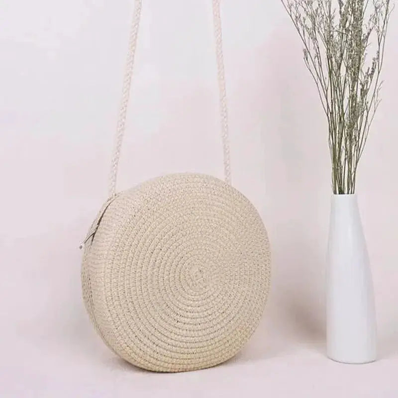 Minimalist round straw bag with a long beige crossbody strap, women's handbag