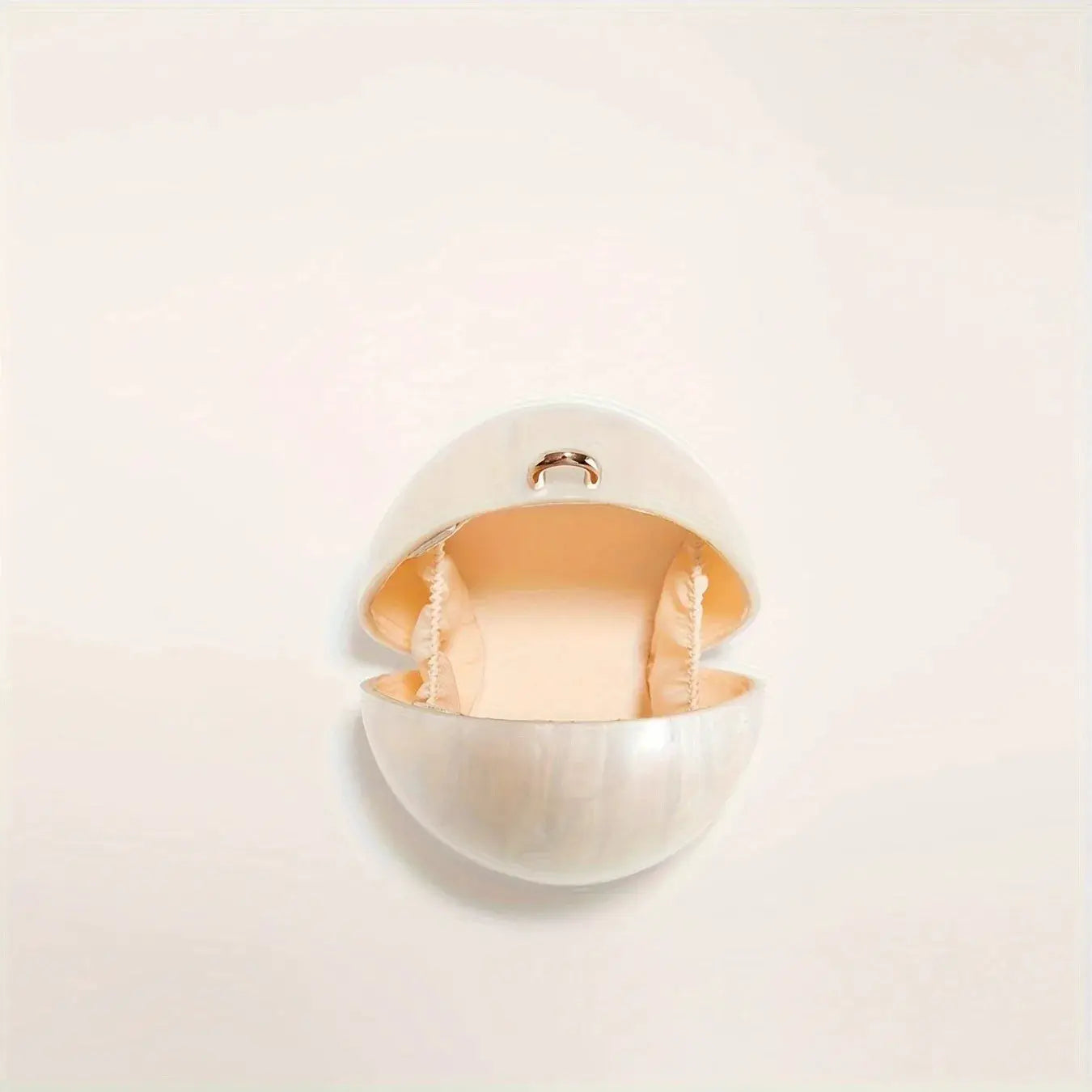 Egg-shaped acrylic clutch with pearl beading, white exterior and peach satin interior by Simples Market