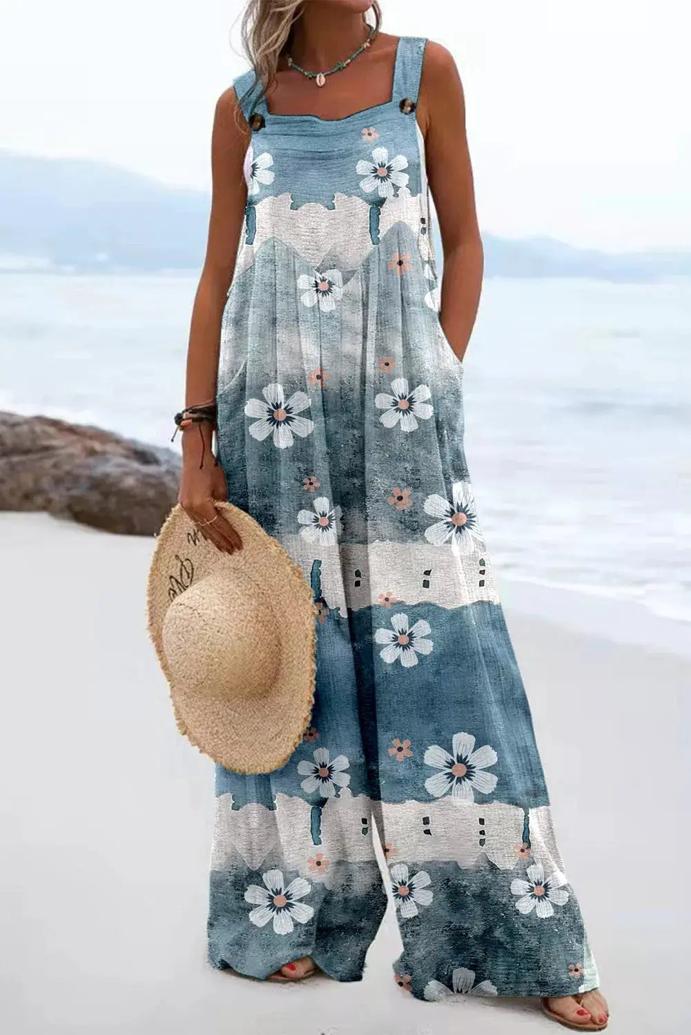Jumpsuit with vintage floral print in blue denim tones, sleeveless with buttoned straps and wide legs
