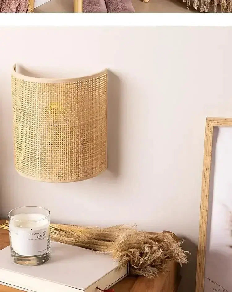 Rattan wall lamp sconce with natural beige woven shade mounted on a wall above a shelf.