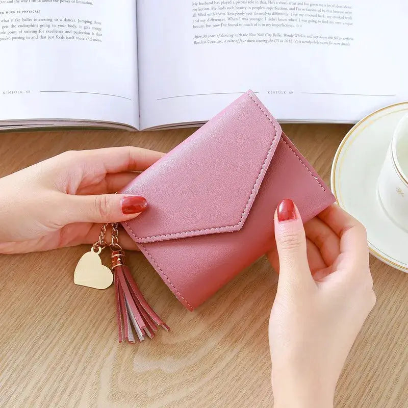 Pink PU leather women's wallet with tassel charm and heart keychain.