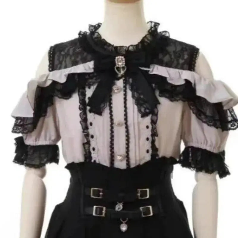Lolita blouse in pale pink and black lace with off-shoulder ruffles, bow, and belt on mannequin.