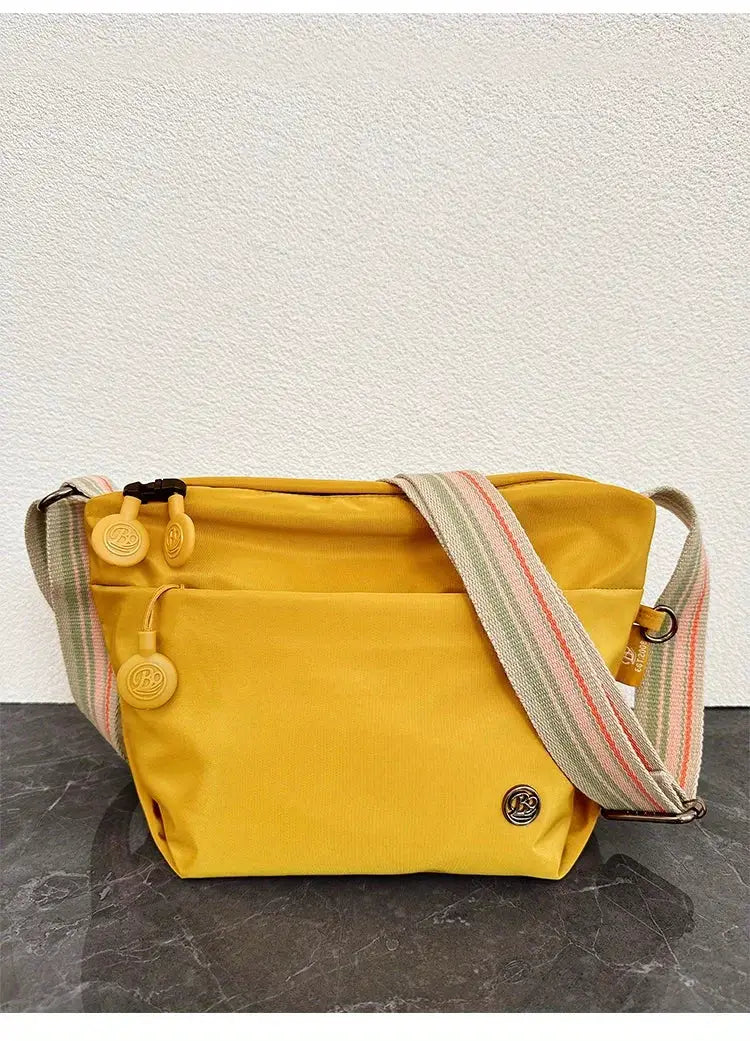 Yellow ultra-light nylon crossbody bag with an adjustable striped wide strap and zipper closure.