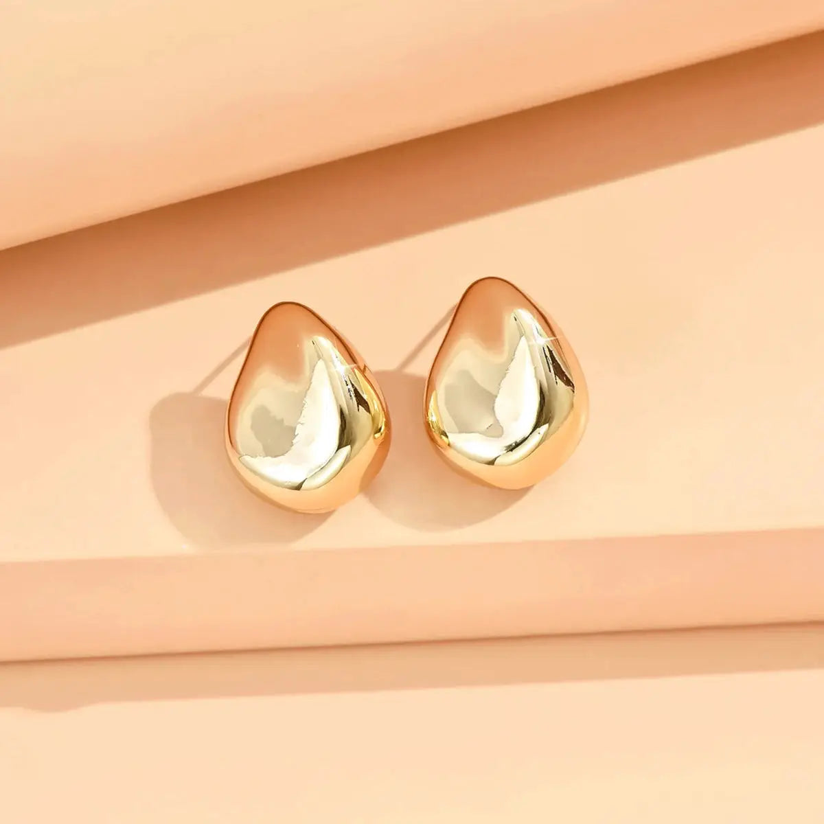 Pair of geometric irregular teardrop stud earrings in rose-gold and silver-tone metal.