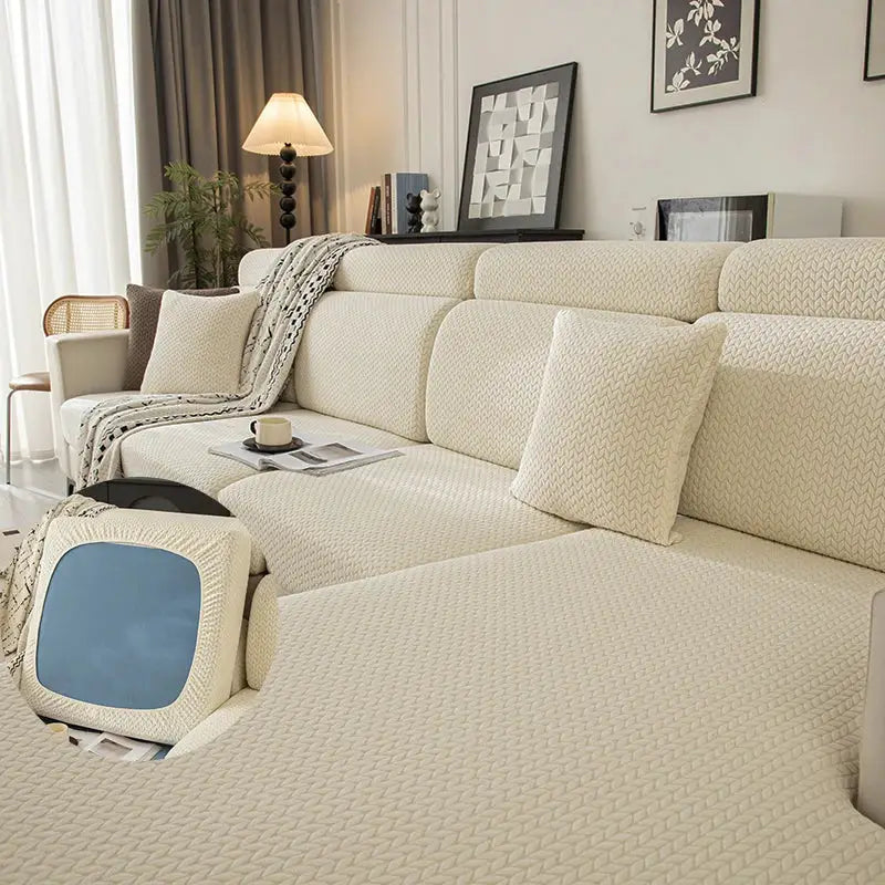 Sofa cover in cream string-knit with elastic edges; matching cushions on a sectional.