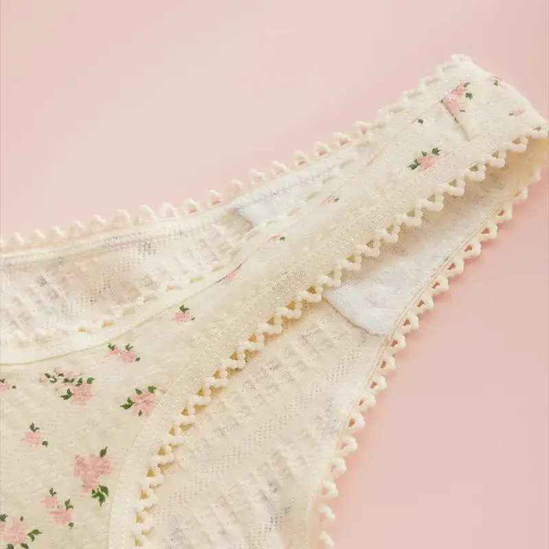 Women's ivory floral print thong with pom-pom trim; soft cotton fabric.
