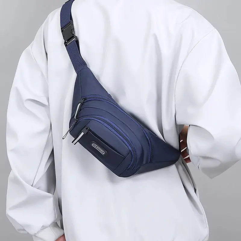 Men's navy blue Simples Market waist bag with multiple zip pockets worn crossbody.