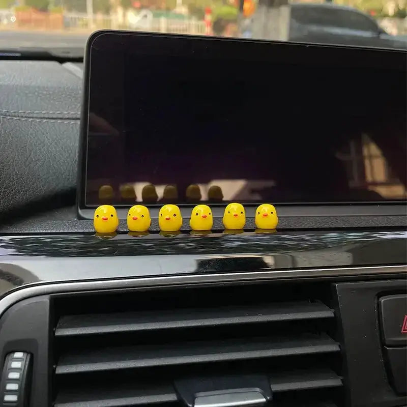 Car interior decorations: six yellow chick ornaments lined on the dashboard in front of the center display.