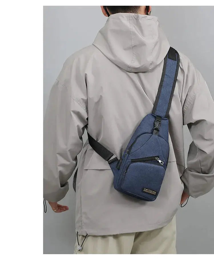 Men's blue canvas chest bag with front zip pocket, worn crossbody with adjustable strap.