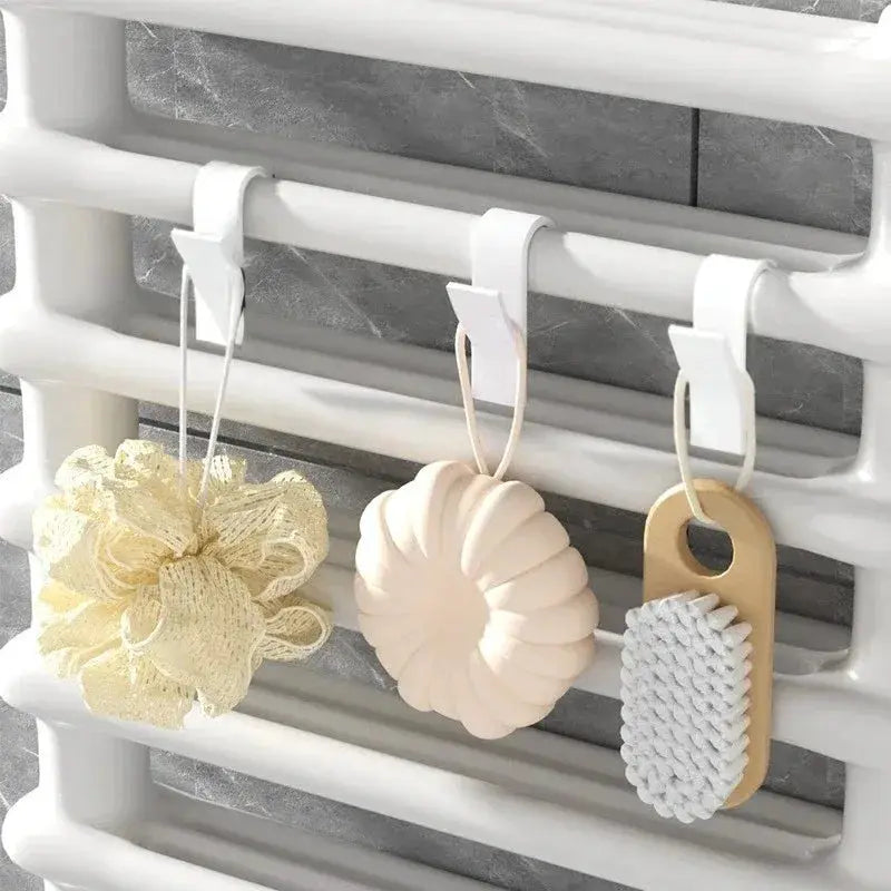 Simples Market bathroom towel rail hooks on a white heated radiator holding 3 accessories: loofah, shell sponge, brush.