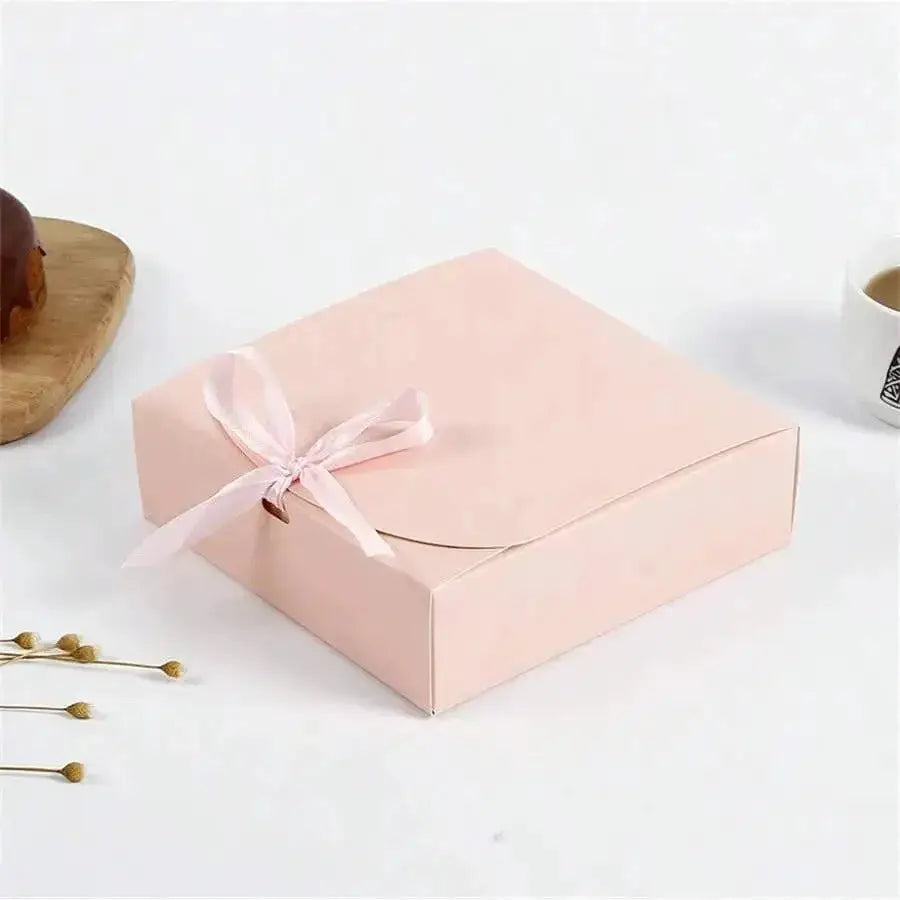 Pink gift box with lid and pale pink ribbon bow on white background.