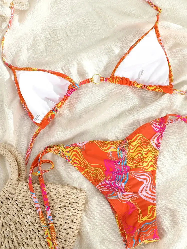 Triangle bikini set in orange abstract print with white lining includes a woven straw tote bag