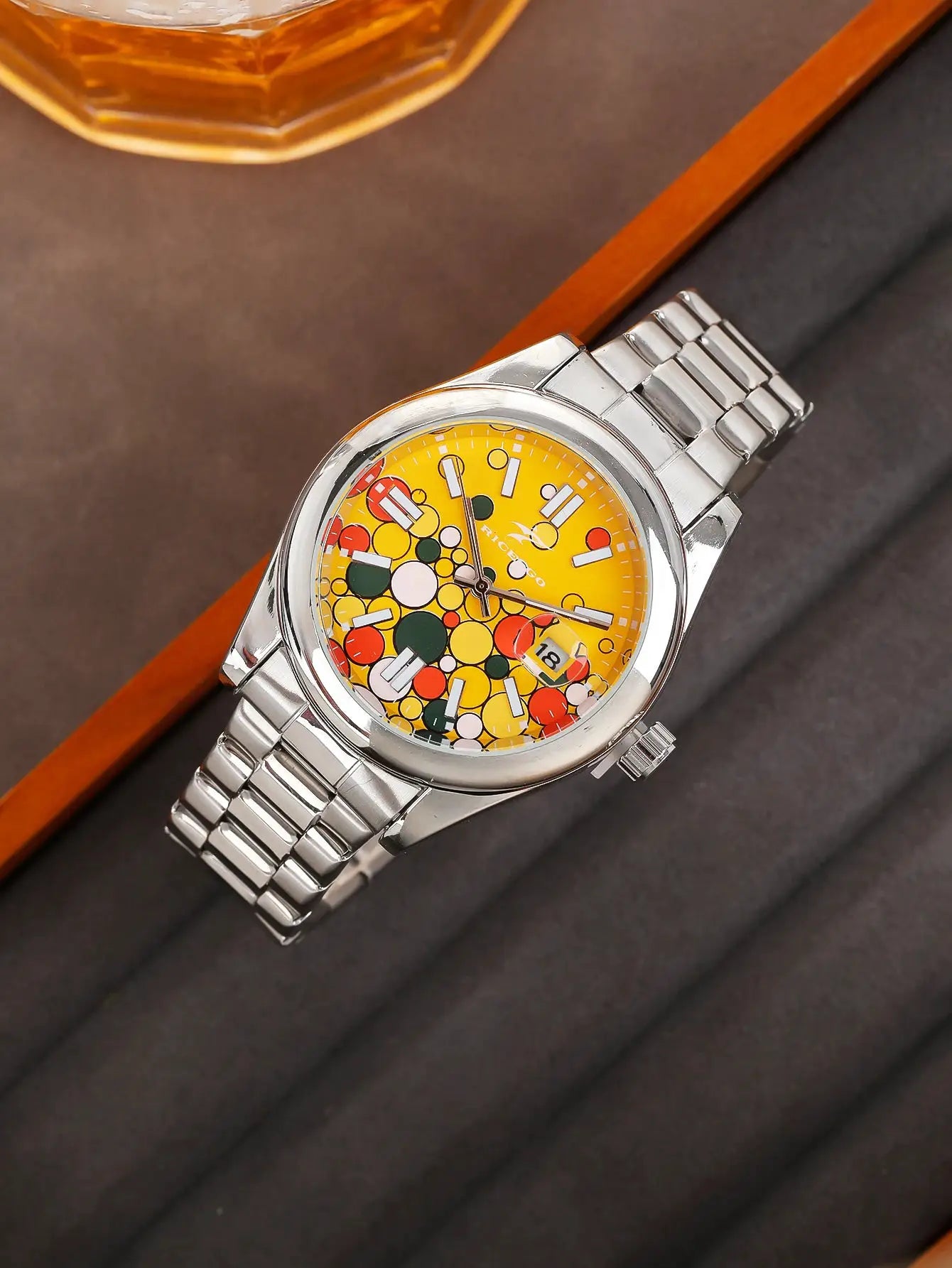 Men's stainless steel quartz watch with a bright yellow dial, colorful dot pattern, and date display.