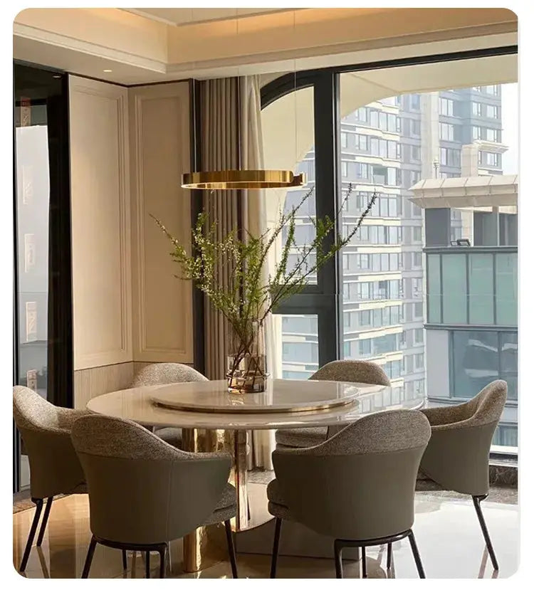 Gold ring ceiling chandelier over round white dining table with six gray upholstered chairs in a modern dining room