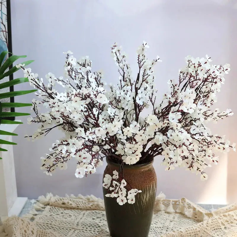 Artificial cherry blossom gypsophila flowers arranged in a ceramic vase with brown branches and white blossoms
