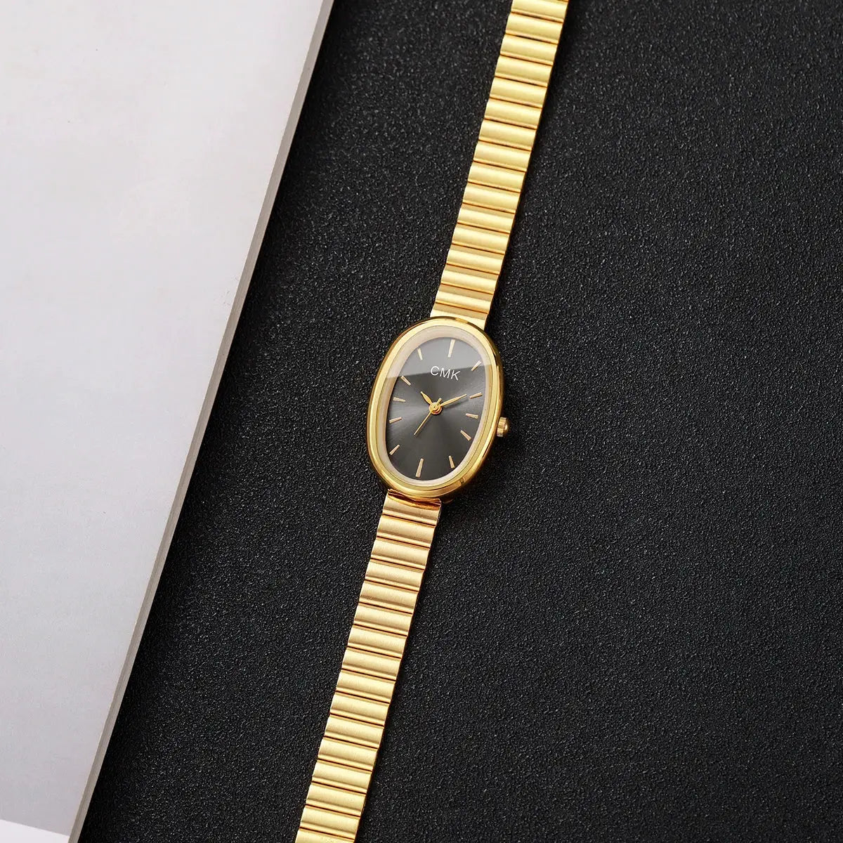 Gold-tone oval-dial women's wristwatch with a slim metal bracelet and CMK on the dial