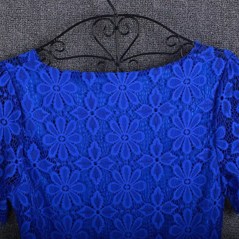 Blue lace blouse top for women displayed on a hanger, featuring an intricate floral lace pattern and short sleeves