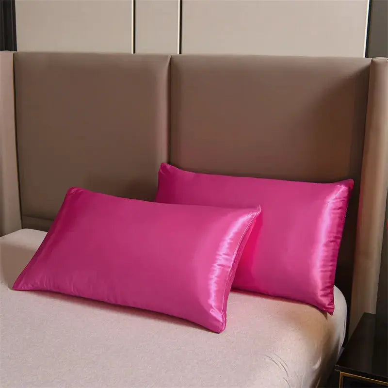 Pink satin pillows on a beige upholstered bed with headboard