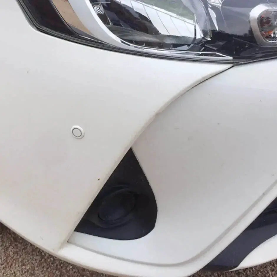 Parktronic parking sensor kit on white car bumper; round sensor visible